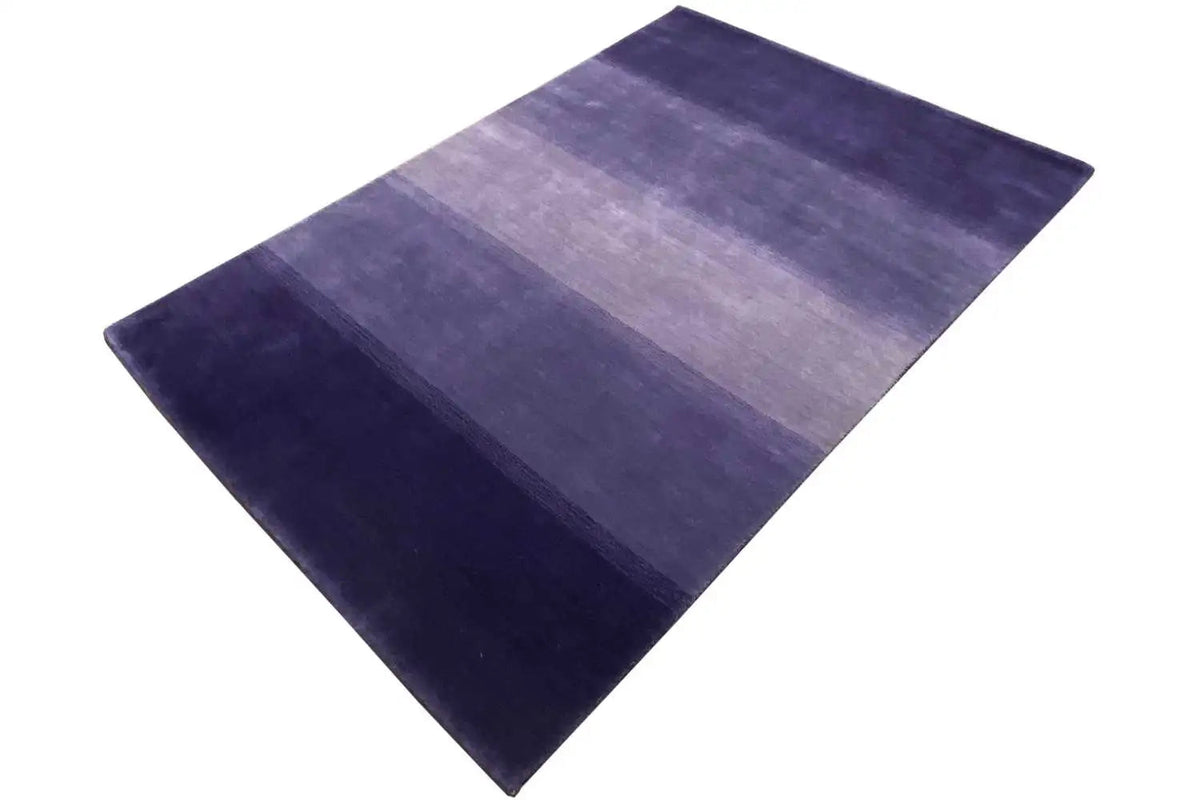 Gabbeh rug laid at an angle, horizontal striped pattern in dark blue and violet.