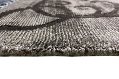 Gabbeh rug close-up: woven texture in gray, black fringes along the edge