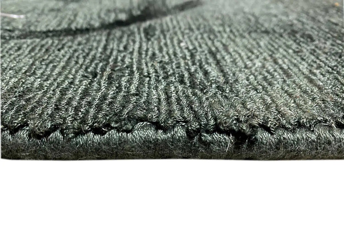 Close-up: dark green Gabbeh rug with a dense pile and blue fringes