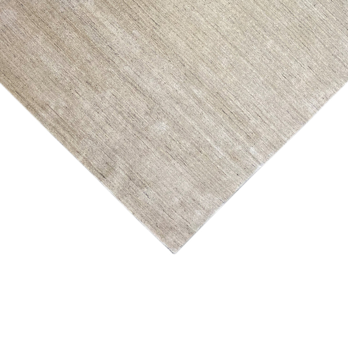 Corner of a beige low-pile rug, edges neatly bound, mottled texture