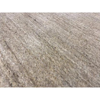 Close-up: beige-brown, mottled carpet pile with a visible, irregular texture