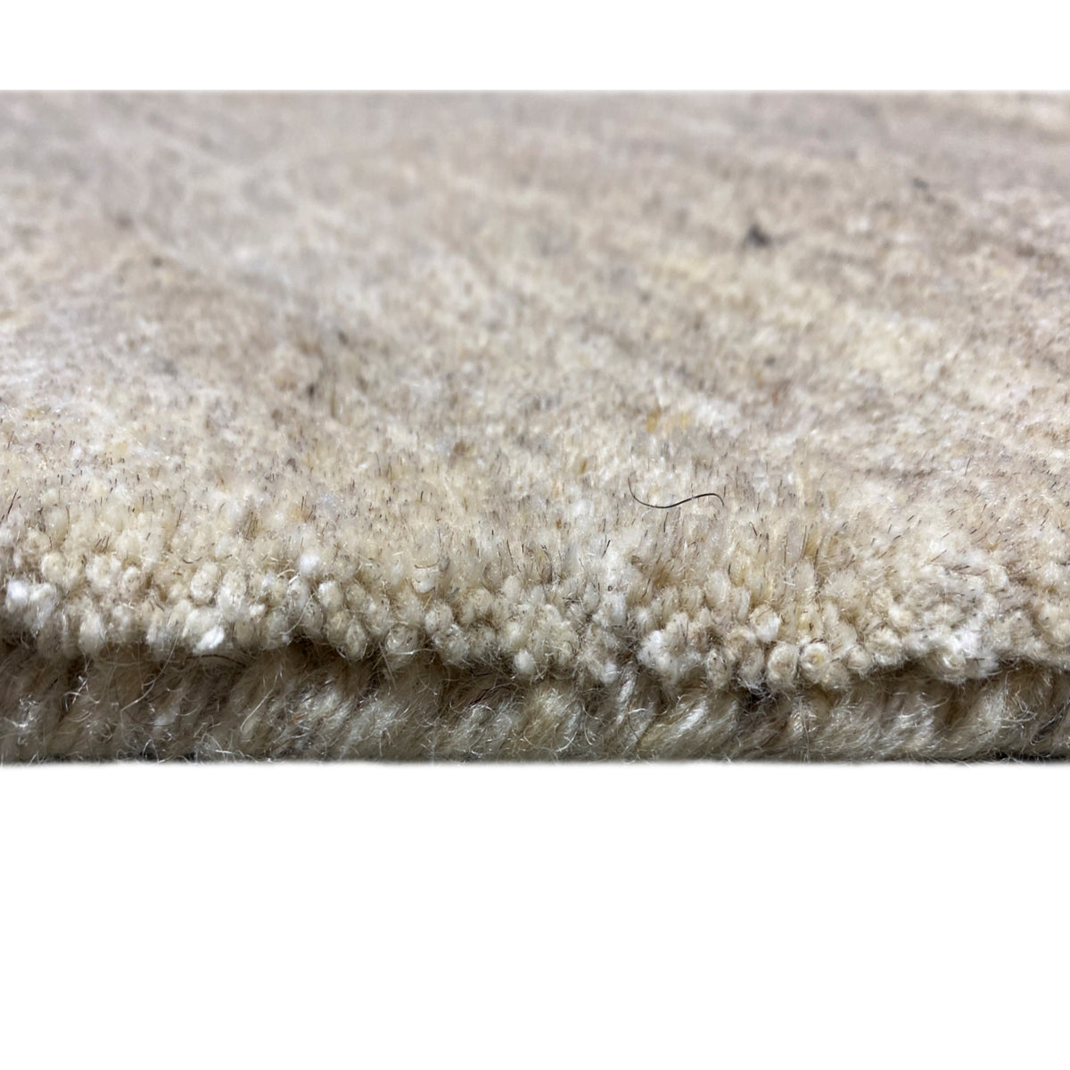 Carpet edge in detail: short pile fibers and multicolored loops, light beige-gray