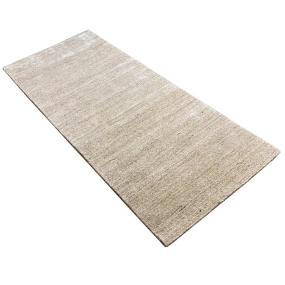 Beige rectangular rug lying at an angle, with a fine relief and fiber texture