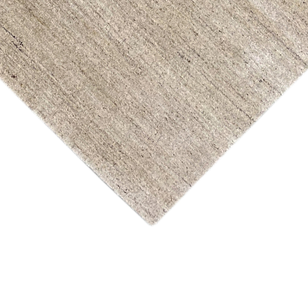 Close-up of a carpet corner: light, mottled surface with fine fiber detail