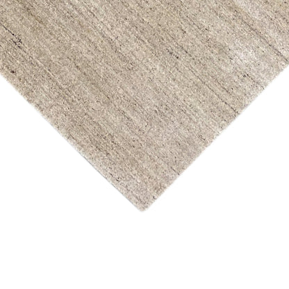 Close-up of a carpet corner: light, mottled surface with fine fiber detail