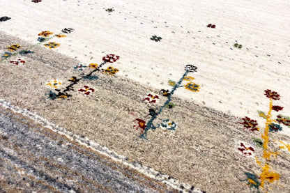 Detailed view: beige rug with colorful cross and dot motifs and a gray edge