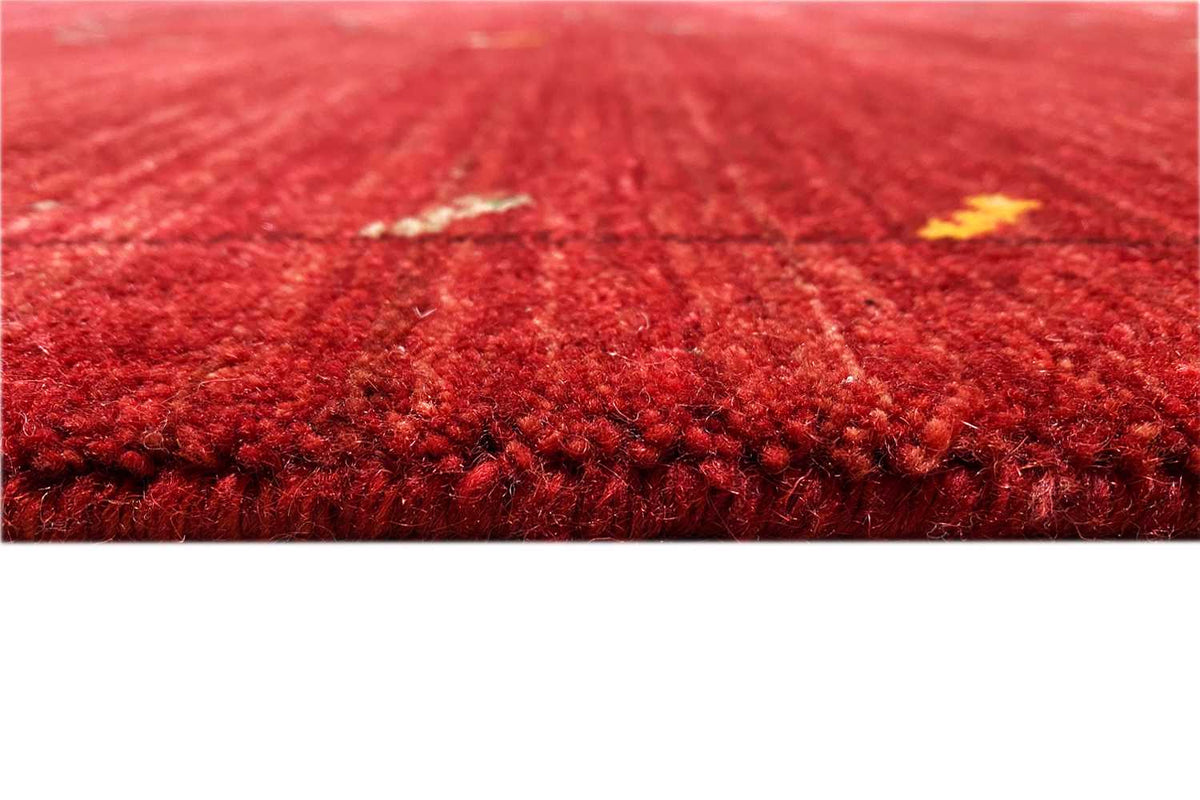 Close-up: red Gabbeh rug with dense pile and small touches of color