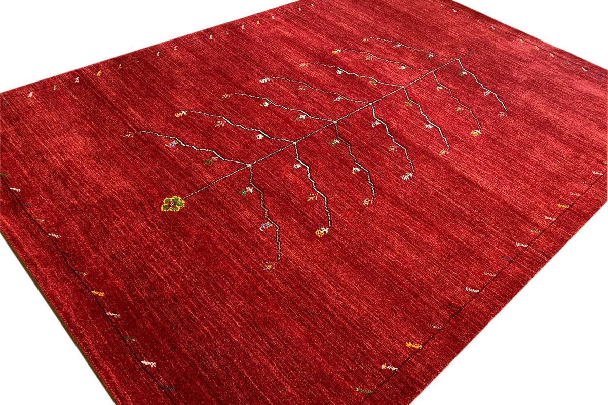 Red Gabbeh rug with a beige tree-vine pattern, spread out