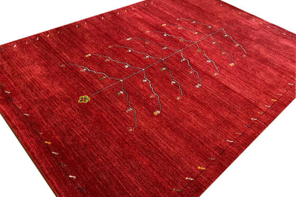 Red Gabbeh rug with a beige tree-vine pattern, spread out