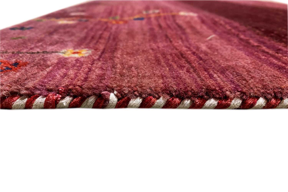 Close-up of Gabbeh rug: burgundy pile with twisted fringes in cream and red