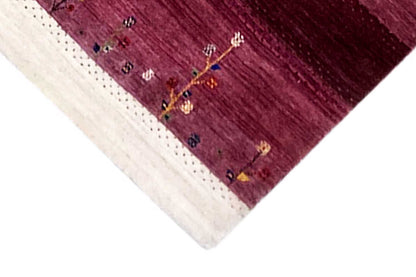 Gabbeh rug corner view: burgundy field, cream-colored border, small patterned lines