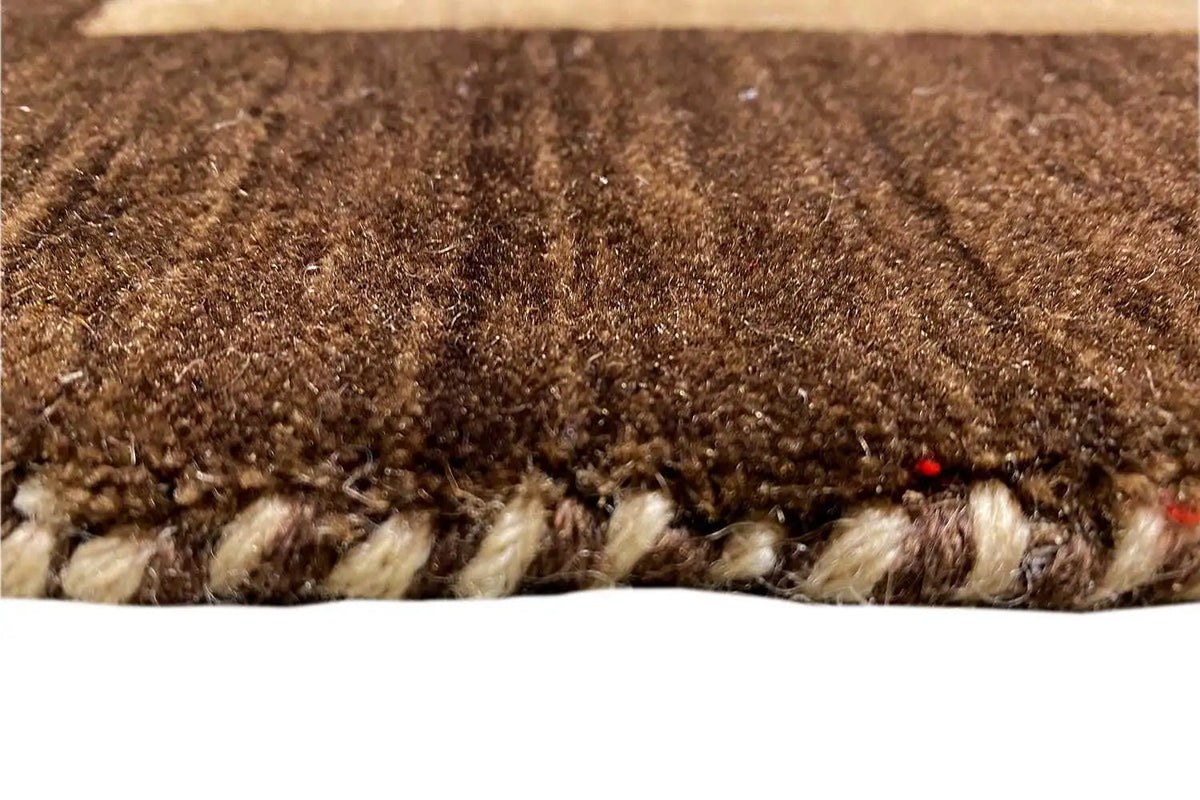 Carpet pile in detail: brown and beige texture with a wavy edge.