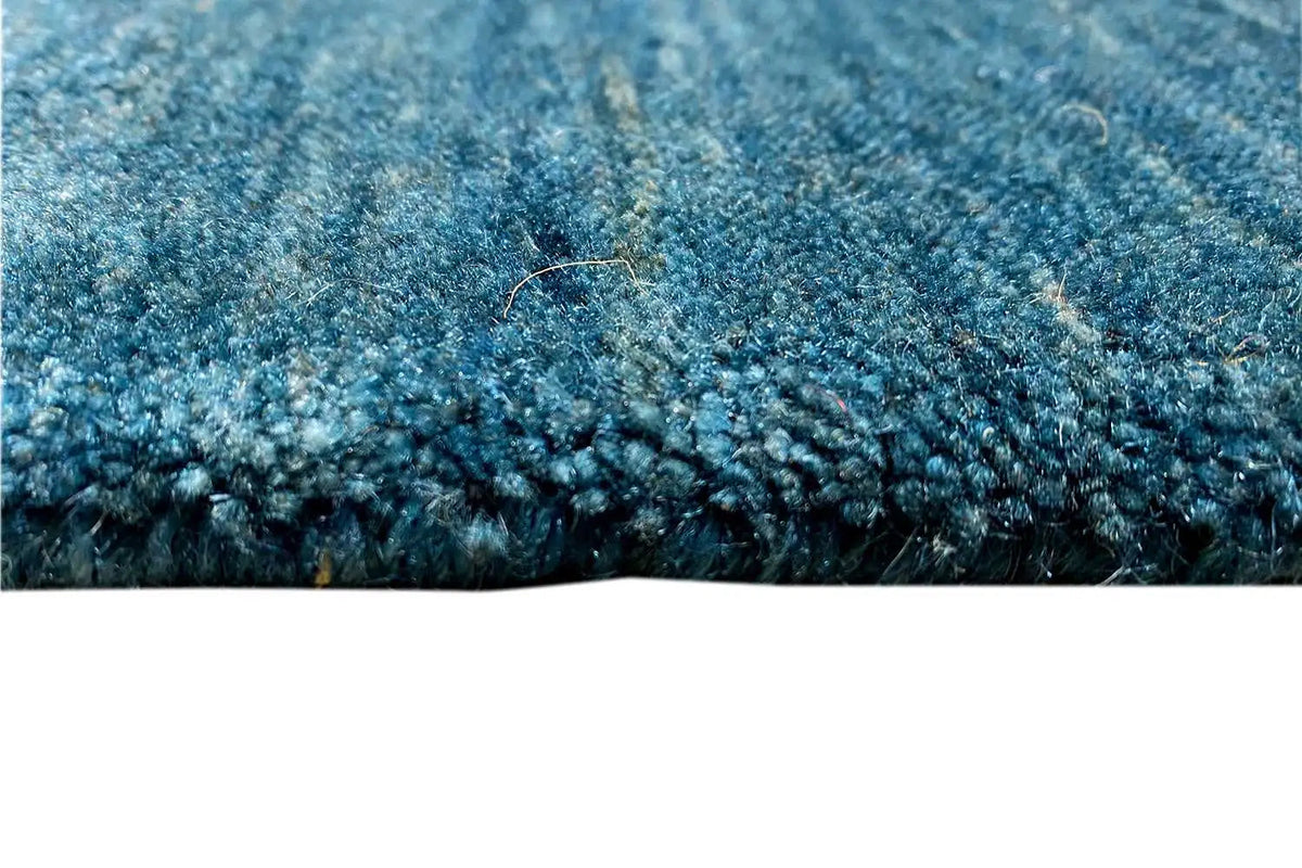 Blue Gabbeh rug with dense pile texture along the edge and rug fringe