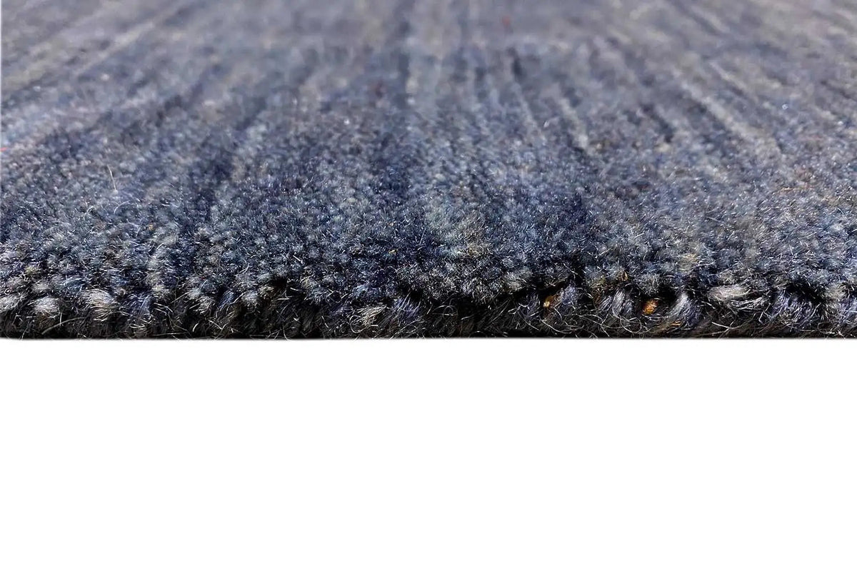 Close-up: blue Gabbeh rug with a short pile and bound edge.