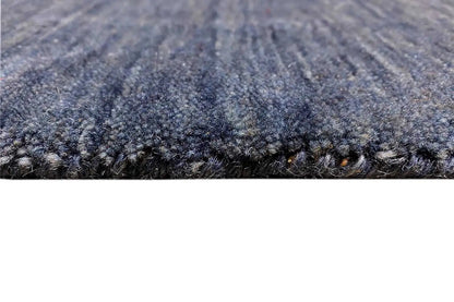 Close-up: blue Gabbeh rug with a short pile and bound edge.