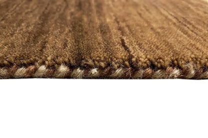 Gabbeh rug detail: brown pile texture and bound edge with tassel threads