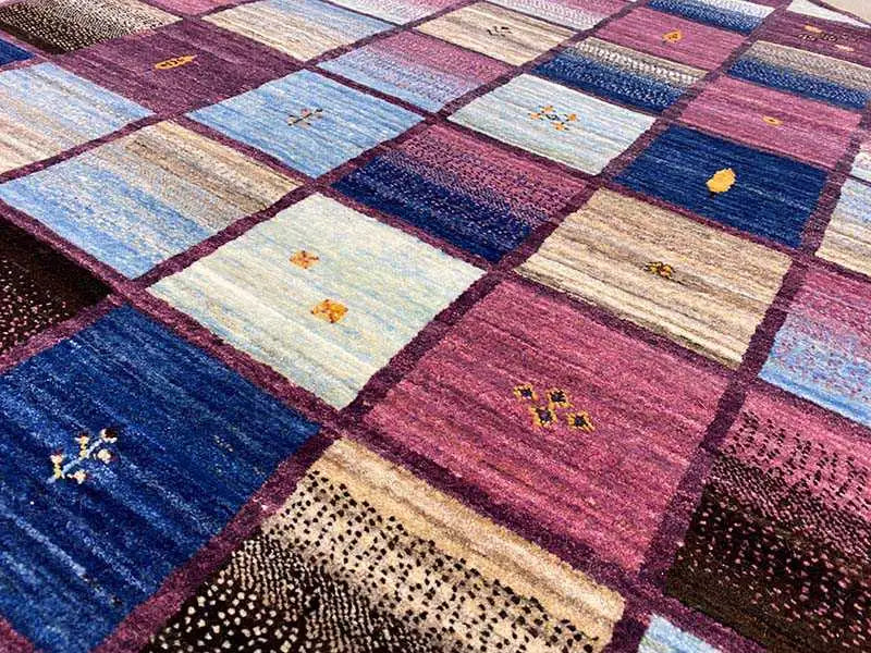 Close-up of a Gabbeh rug: patchwork squares, blue and burgundy areas with patterns