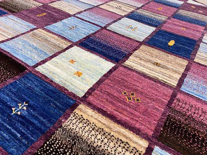 Close-up of a Gabbeh rug: patchwork squares, blue and burgundy areas with patterns