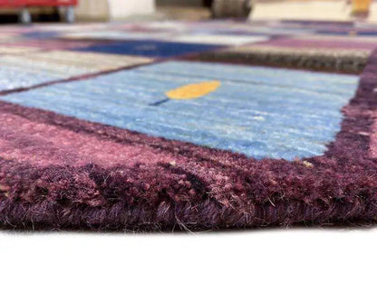 Detail of the edge of a Gabbeh rug with a dense violet-bordeaux pile