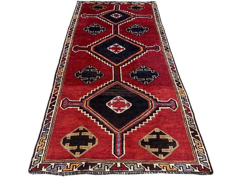 Lori rug in red with a black central area and star-like patterns in cream, blue, and yellow.