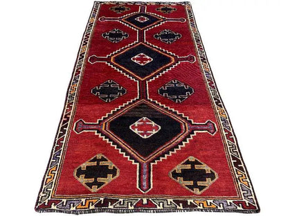 Lori rug in red with a black central area and star-like patterns in cream, blue, and yellow.