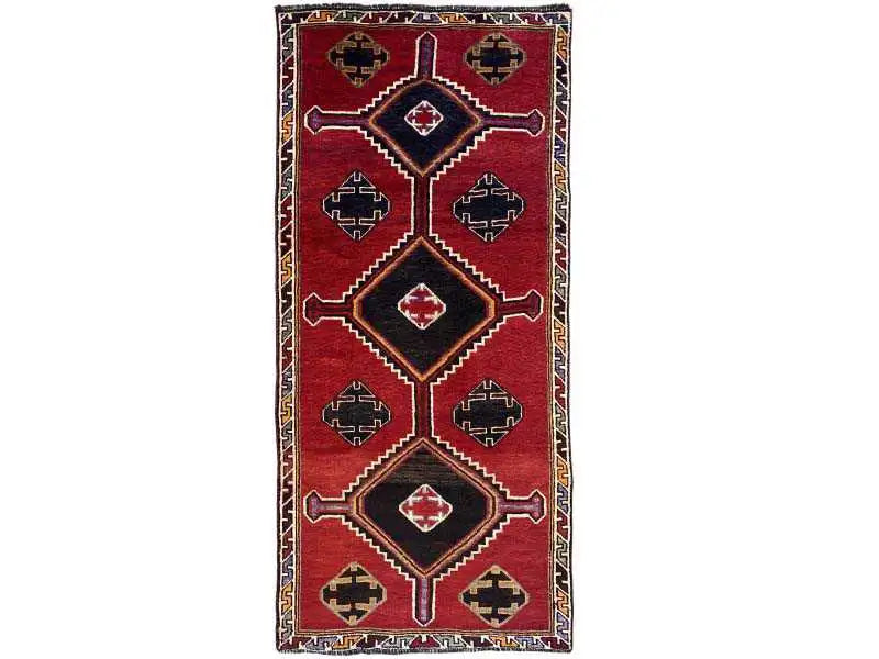 Rectangular Lori rug with a red background, black border, and symmetrical diamond ornaments.