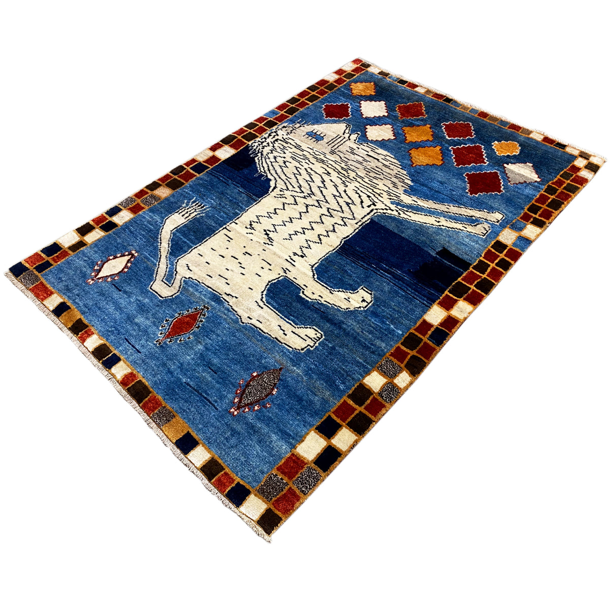 Blue Gabbeh rug viewed at an angle: white lion, red/blue ornaments, and a diamond-patterned border.