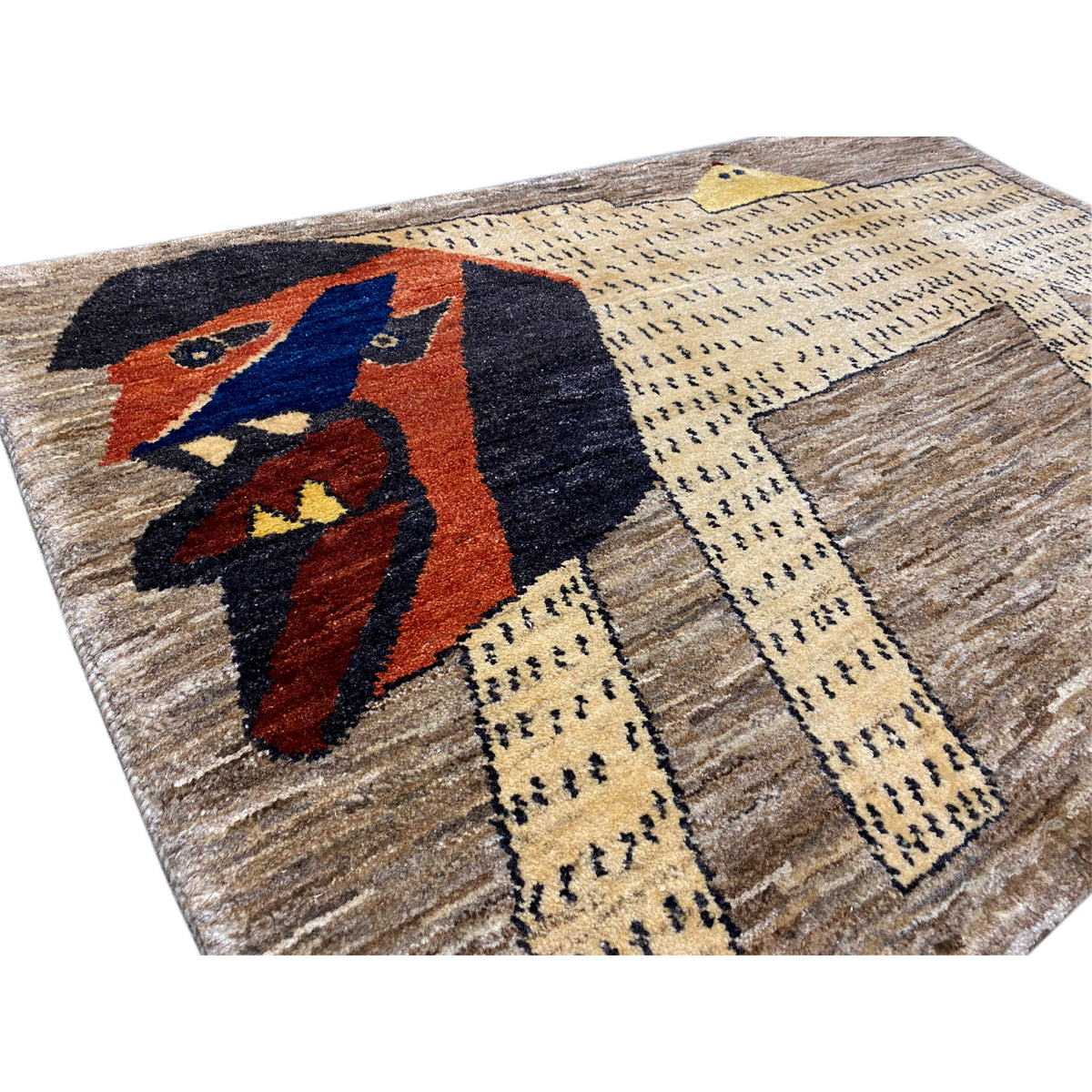 Close-up of a Gabbeh rug: stylized lion figure in blue, red and black on beige