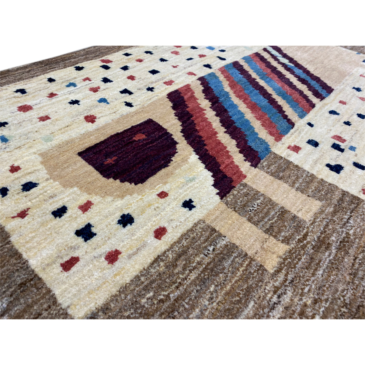 Close-up of a Gabbeh rug: cream-colored pattern with dark squares, stripes, and dots