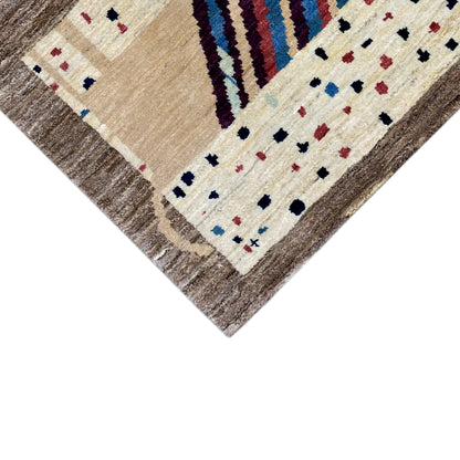 Gabbeh rug corner viewed at an angle: cream, brown, colorful stripes and dotted patterns