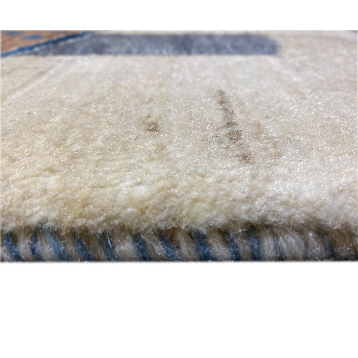 Close-up of Gabbeh rug: beige pile with blue border stripes