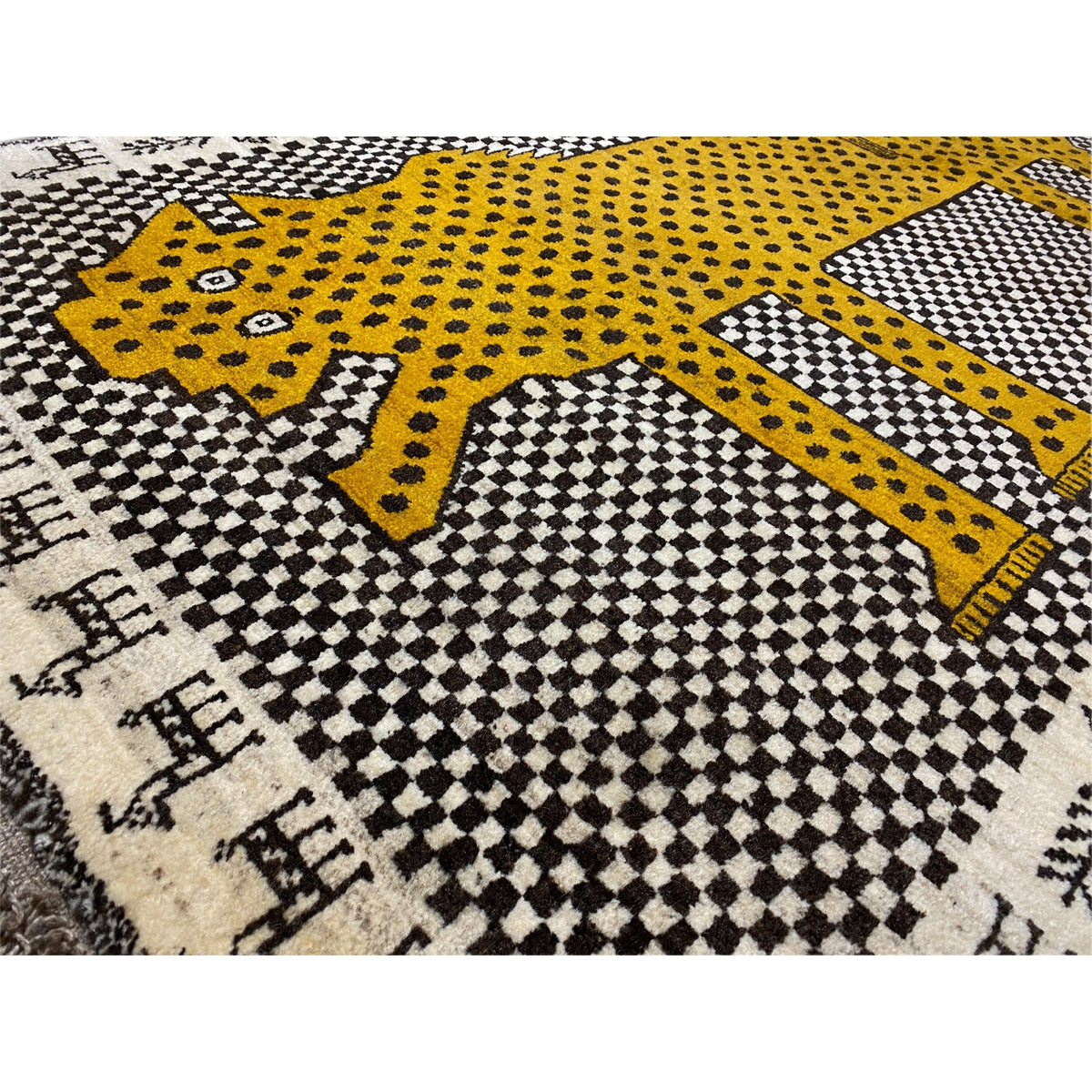 Close-up: Gabbeh rug with a yellow leopard figure, dotted decoration and checkered pattern