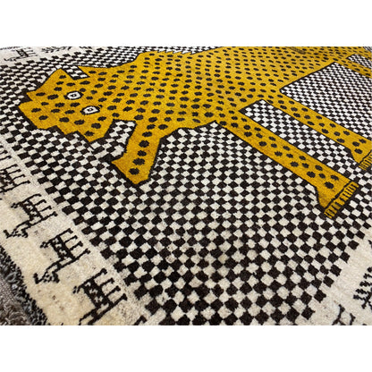 Close-up: Gabbeh rug with a yellow leopard figure, dotted decoration and checkered pattern