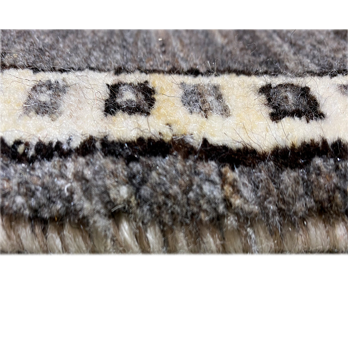 Rug edge with dense fringes in gray and ecru