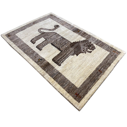 Gabbeh rug with beige and dark stripes and a lion appliqué, photographed at an angle.