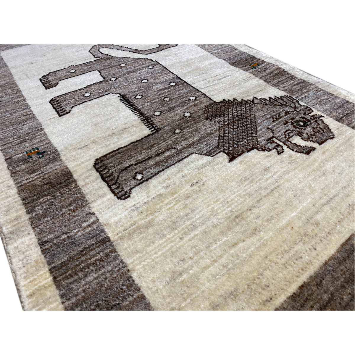 Close-up of a Gabbeh rug: beige background, dark lion with embroidered details.