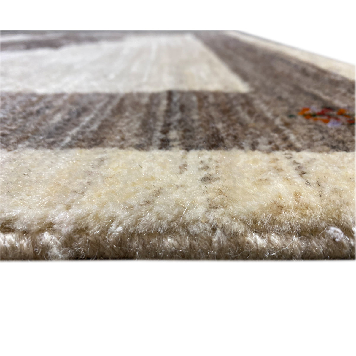 Close-up view of the carpet edge: short beige pile with dark accents and stripes.