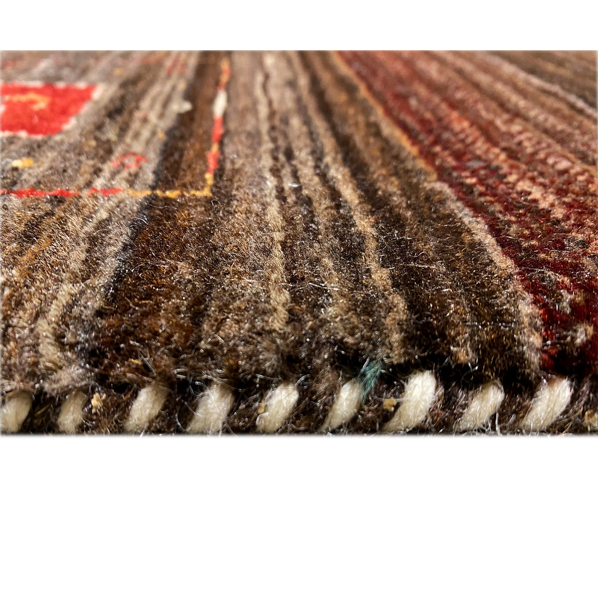 Close-up of the carpet surface with dense pile, brown-beige and colorful embroidered areas