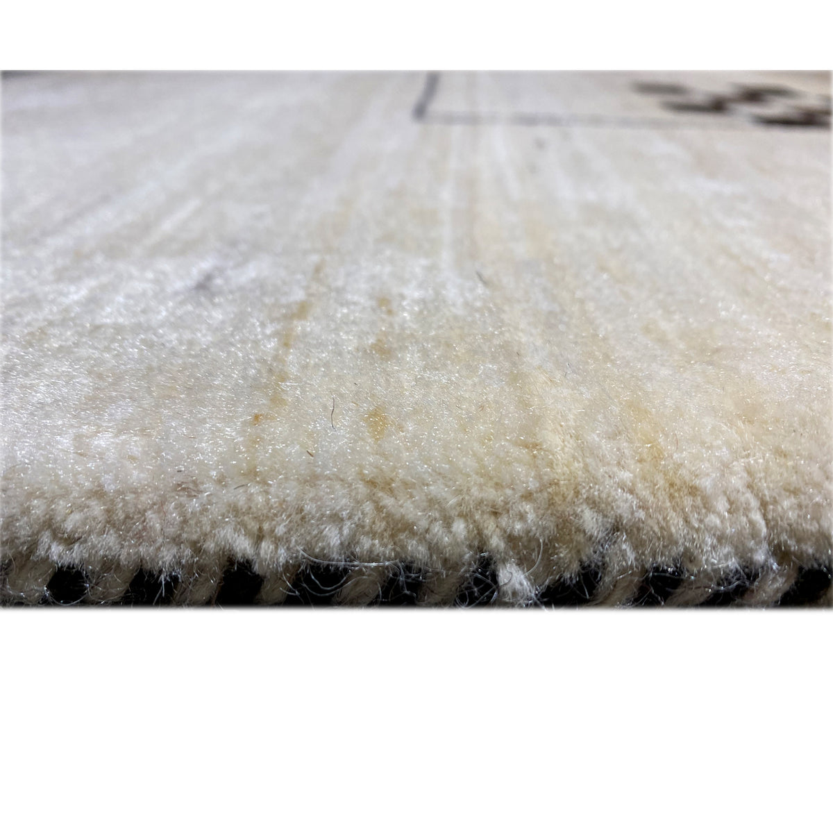 Rug edge with dense, light beige pile and a visible side edge
