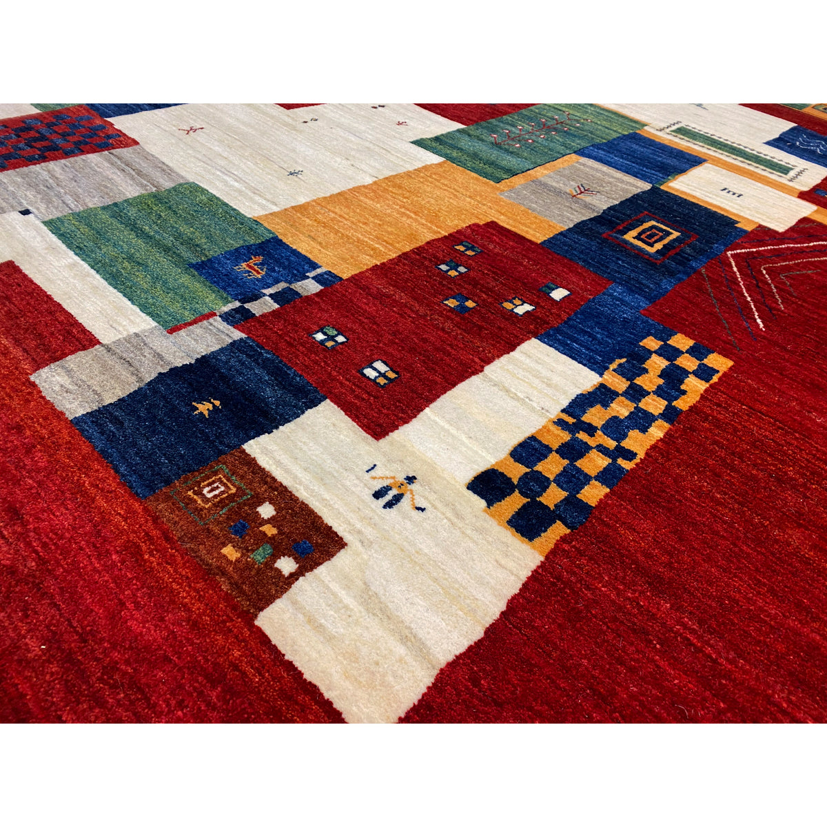 Gabbeh Luri rug close-up: dense patchwork of red, blue, green, and beige