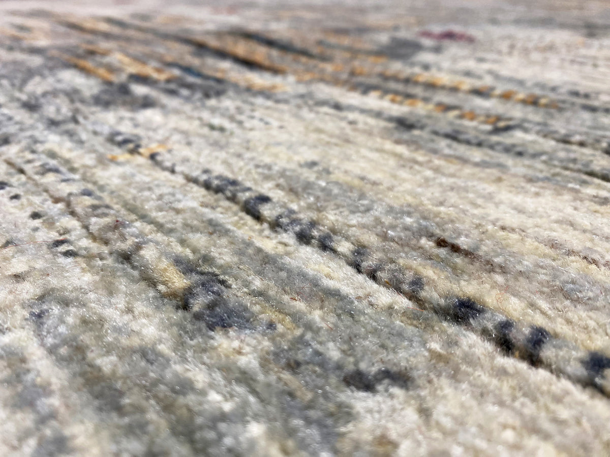 Gabbeh-Luri rug close-up: light gray texture with dark and golden stripes