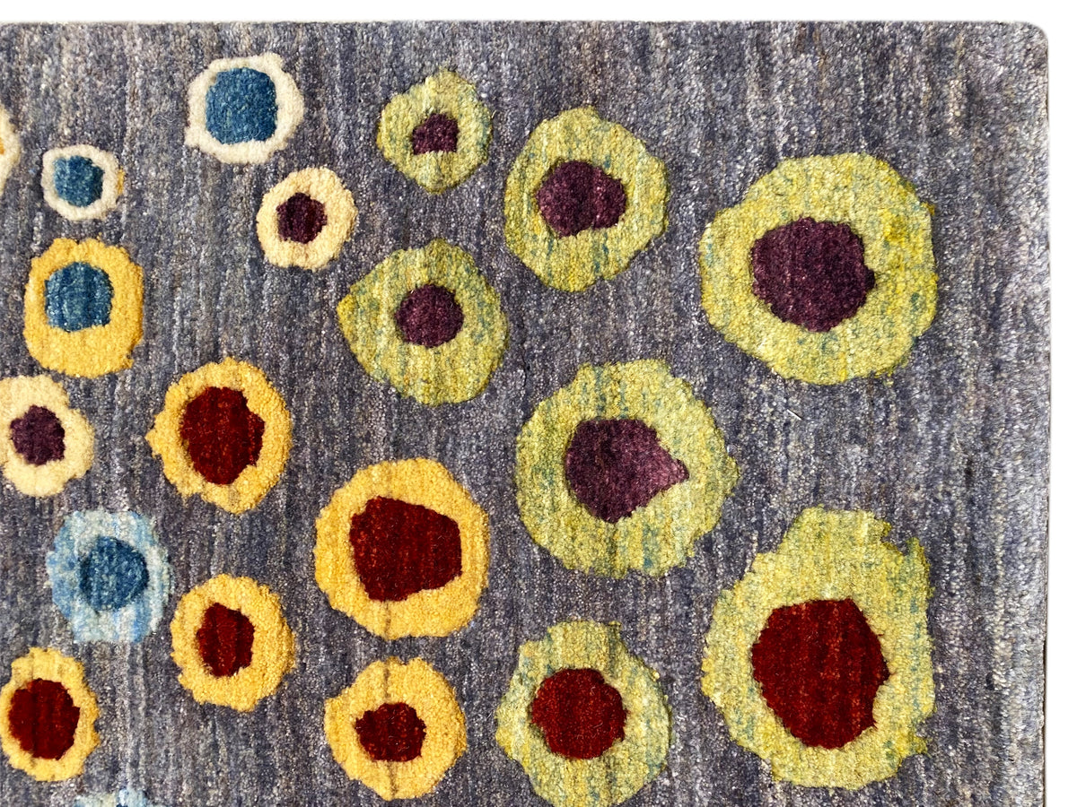 Close-up of a Gabbeh-Luri rug: gray wool with yellow, red, and blue circular rings