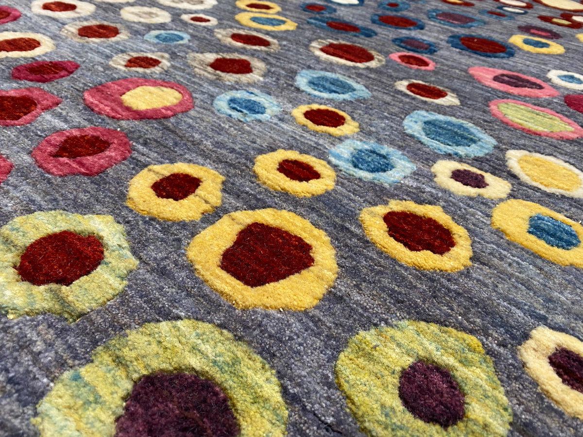 Gabbeh-Luri rug close-up: colorful circular and oval motifs on a gray background