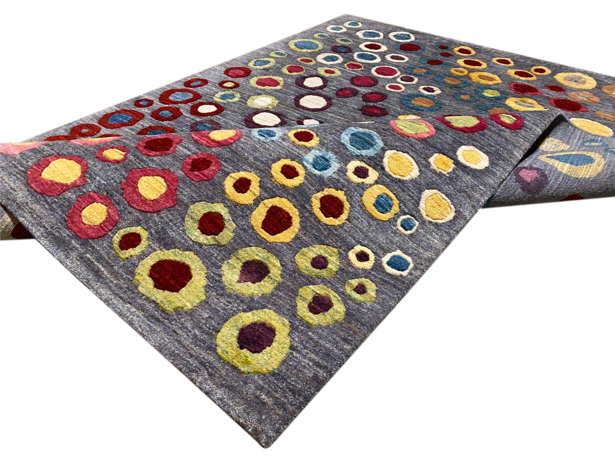 Gabbeh Luri rug shown rolled up: gray background with colorful circular rings