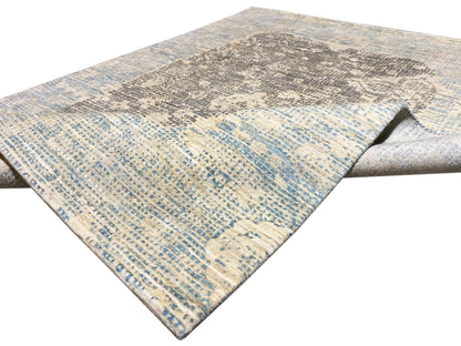 Blue-gray rug with a diagonal patterned area and a lightly hemmed edge
