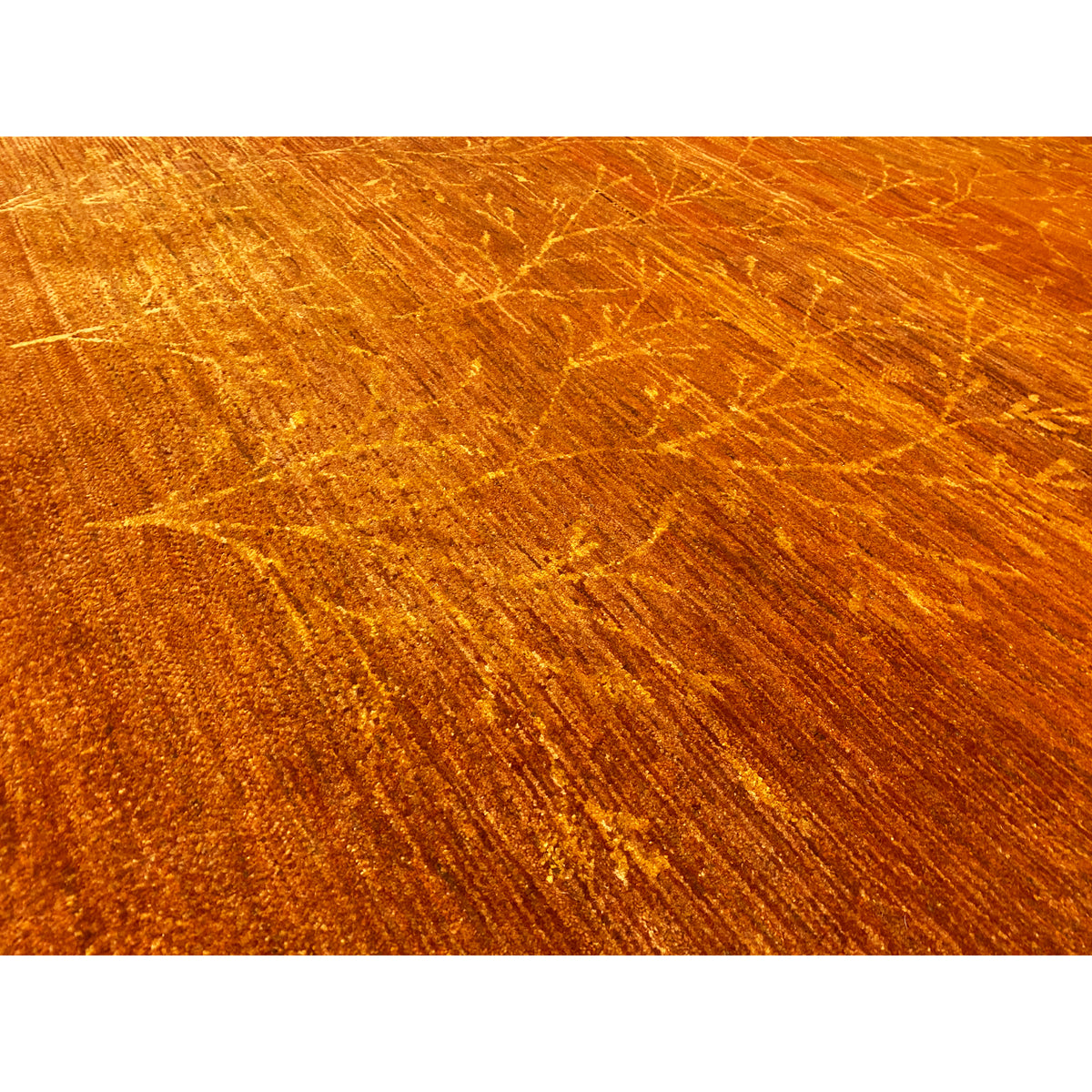 Close-up: orange-brown carpet with gold-colored ornamental lines in the pile