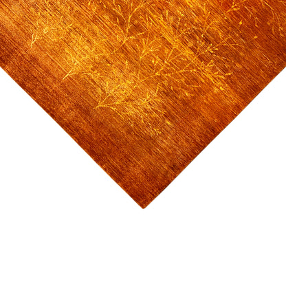 Corner of an orange-brown rug with a gold-colored linear ornament