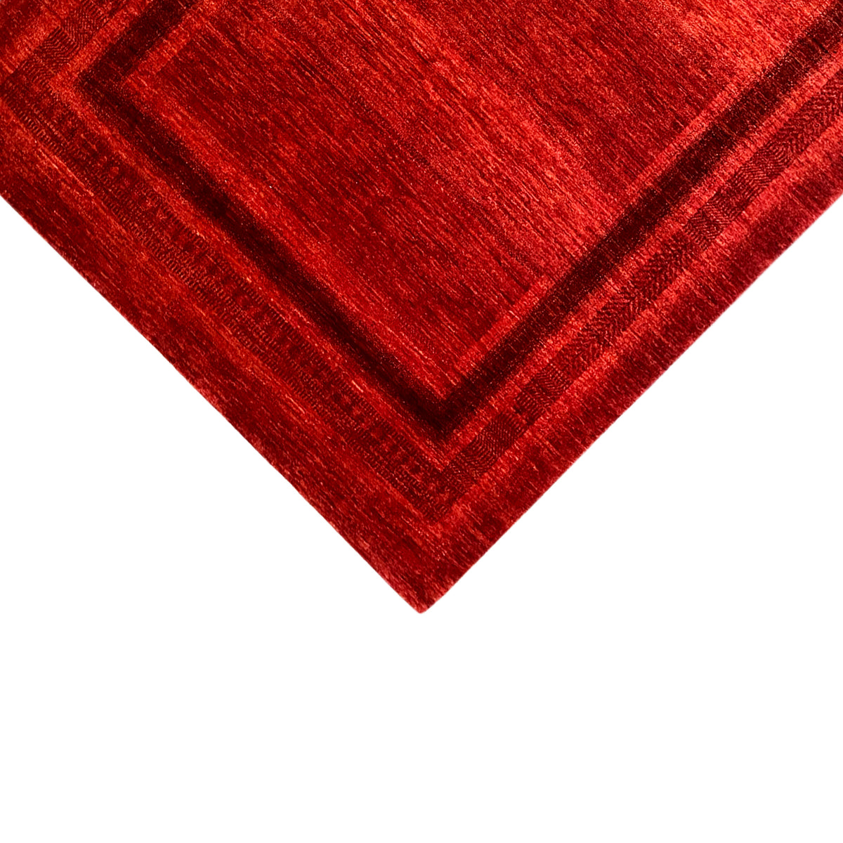 Close-up: red carpet with a geometric border and textured pile