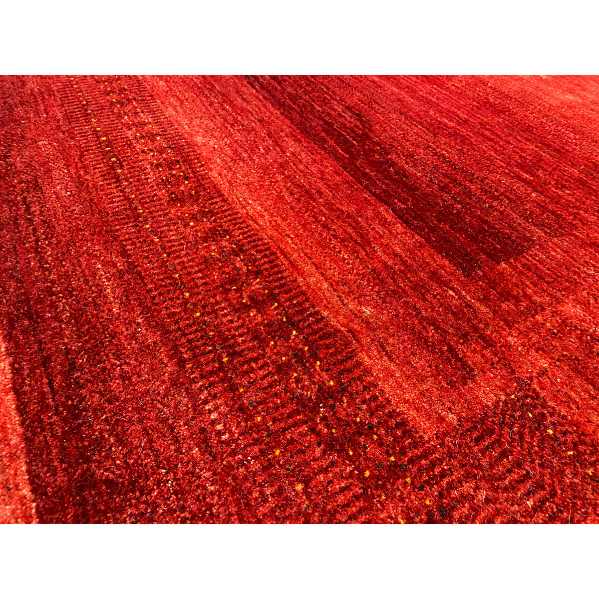 Close-up of a Gabbeh-Luri rug: shimmering red surface with a linear texture