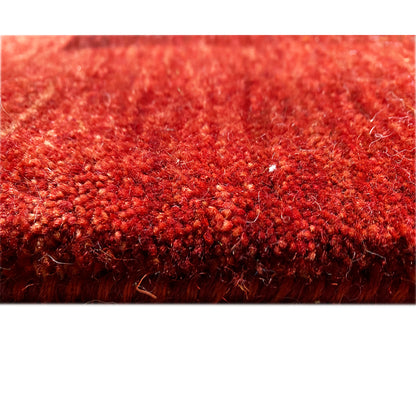 Close-up of a Gabbeh Luri rug: dense red pile with visible fiber tufts